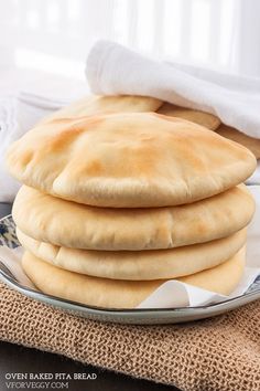 a stack of bread sitting on top of a plate next to a white towel and window