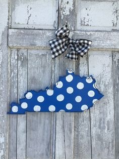 a blue and white polka dot state shaped door hanger with a bow on it