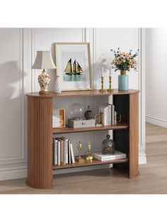 a shelf with books, vases and pictures on it in front of a white wall