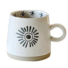 a white coffee cup with black designs on the outside and inside, sitting in front of a white background