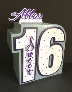 a white and purple birthday cake with the number sixteen on it's side, in front of a black background