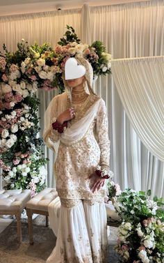 a woman in a white outfit standing next to flowers