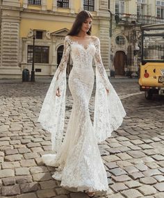 a woman in a white dress standing on a cobblestone street