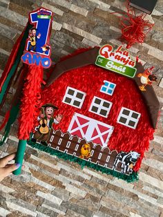 a child's birthday cake with a red barn on top and decorations around it