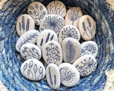 some rocks are sitting in a basket with blue and white designs on them, along with other stones