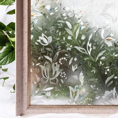 an image of a frosted glass window with leaves and flowers on it in front of a potted plant