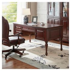 an office desk and chair in a room with hardwood floors, large windows, and white rug