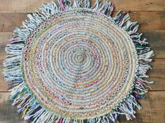 a multicolored round rug with fringes on a wooden floor, top view