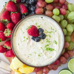 an easy cream cheese fruit dip recipe in a bowl surrounded by grapes, strawberries and limes