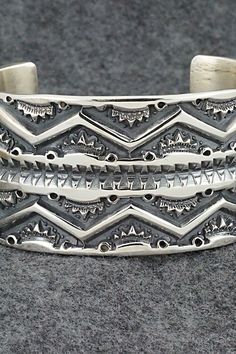 This stunning sterling silver bracelet was made by Navajo silversmith Jerrold Tahe. The inside is signed J. Tahe and stamped sterling.Size: 6" (will fit up to a 7 1/2" wrist)Gap: 1 1/2"Width: 1 1/2"Free shipping on all orders! We ship with USPS and always include tracking. All orders ship within a day of payment.Returns are accepted up to 30 days after you receive your order. Just send us a message. Our shop offers cash back or store credit. The item must be returned in new condition. Artisan Sterling Silver Bracelet With Intricate Design, Artisan Sterling Silver Bracelet With Oxidized Finish, Southwestern Sterling Silver Polished Bangle Bracelet, Southwestern Polished Sterling Silver Bangle, Southwestern Sterling Silver Bangle With Polished Finish, Artisan Silver Bracelet With Stamped Details, Southwestern Silver Bangle Jewelry, Southwestern Sterling Silver Cuff Bracelet In Silver, Southwestern Sterling Silver Cuff Bracelet