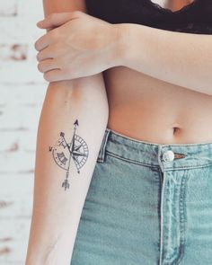 a woman with a compass tattoo on her left arm and the other arm behind her