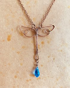 a necklace with a dragonfly charm hanging from it's side on a table