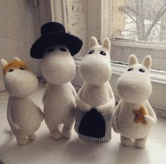 four stuffed animals sitting on top of a window sill