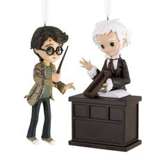 an ornament that looks like two people in harry potter outfits, one holding a wand and the other pointing at something