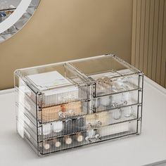 a clear box sitting on top of a white table next to a mirror and clock