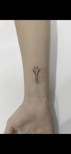 a small giraffe tattoo on the left inner arm and wrist is shown in black ink