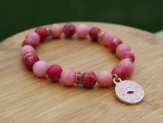 Show your love for OMORI with a handmade bracelet themed around characters from the game! This bracelet inspired by Sweetheart features her signature pink color palette as well as a doughnut charm. This would make a great gift for any fan of the game! The bracelet is made from 8mm genuine rhodochrosite and sea sediment jasper with an enamel doughnut charm. It is strung on elastic cord sized to fit a 6in wrist but will stretch to fit a larger wrist. If you need a custom size, feel free to reach o Playful Pink Charm Bracelets, Pink Round Bead Bracelets For Birthday Gift, Pink Round Beads Bracelets For Birthday Gift, Pink Round Beads Bracelet For Birthday, Pink Charm Bracelets For Birthday Gift, Pink Charms Bracelets For Birthday Gift, Pink Beaded Bracelets For Birthday, Pink Charm Bracelet With Round Beads For Friendship, Pink Round Beads Charm Bracelet For Friendship