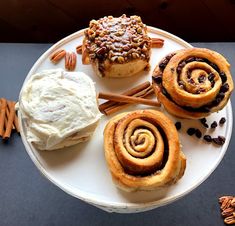 three cinnamon rolls on a plate with whipped cream and pretzels