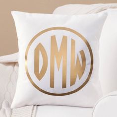 a white couch with a gold monogrammed pillow on it's back cushion