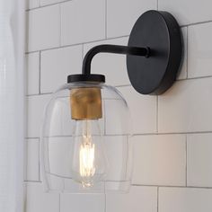 a light that is on the wall next to a white brick wall in a bathroom