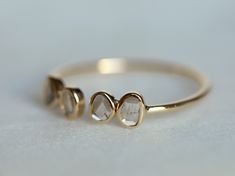 two gold rings sitting on top of a white surface with one diamond in the middle