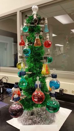 a christmas tree made out of glass bottles and tinsels in an office cubicle