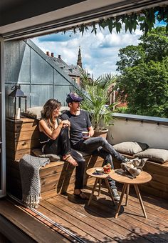 a man and woman sitting on top of a wooden deck