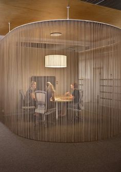 two people are sitting at a table in an office with sheer curtains covering the walls