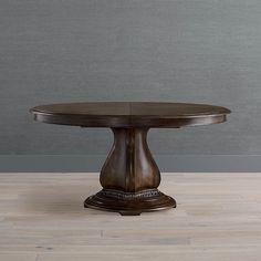 a round dining table with an intricate design on the top and base, against a gray wall