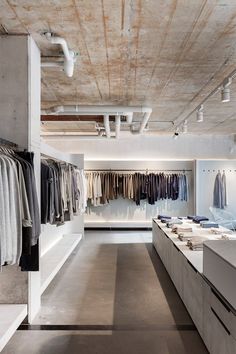 the inside of a men's clothing store with lots of clothes hanging on racks