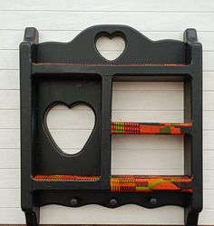 a black shelf with two hearts cut out of the front and sides, on top of a wooden floor