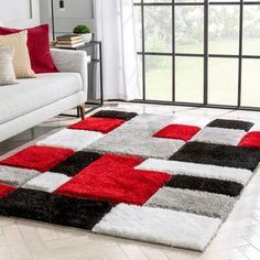 a living room with a white couch, red and black rugs and a large window