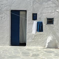 clothes hanging out to dry on a line in front of a white building with blue doors