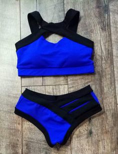 two pieces of blue and black swimsuit sitting on top of a wooden floor