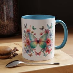 a blue and white coffee mug sitting on top of a wooden table next to a spoon