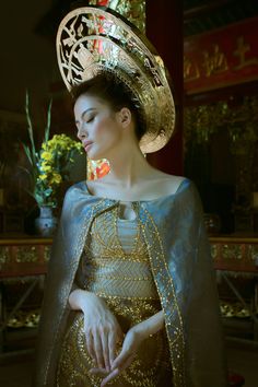 a woman wearing a gold and blue dress with a large hat on top of her head