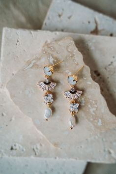 a pair of earrings sitting on top of a stone slab next to a white rock