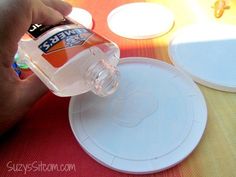 a person is pouring water into a plastic bottle on top of a table with plates