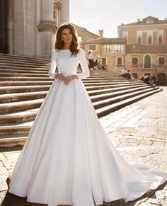 a woman in a white wedding dress standing on steps