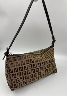 A stunning Fendi Pochette shoulder bag. Made in the classic Fendi beige/brown Zucca Canvas. Brown leather top handle and Fendi branded silver hardware. Inside there is an internal slip pocket for your valuables. This bag is in great condition with minor signs of wear. The hardware has slight scratches. The external canvas has one small stain (is pictured). Lining is strain free. The leather straps show some slight signs of wear in the form of a few creases. Fendi Pochette, Vintage Fendi Bag, Brown Leather Top, Vintage Fendi, Vintage Casual, Beige Brown, Bag Tags, Leather Top, Silver Hardware