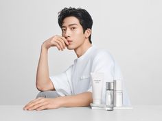 a young man sitting next to some skin care products