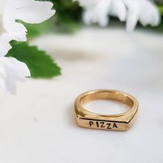 "This is a perfect Christmas gift for your favorite person! This is a fun and flirty band ring hand stamped with \"PIZZA\" in cute uppercase font. It has a flat top which gives it a 90s vibes. This ring is great to wear alone or stack in multiples. All rings come beautifully and simply packaged in an eco-friendly kraft box and twine ready for gifting. About the jewelry: * This stainless steel band ring is plated with gold. * For custom text (up to 7 characters or fewer), please add at checkout. Trendy Personalized Rings For Everyday, Trendy Personalized Everyday Rings, Trendy Personalized Rings For Promise, Trendy Personalized Promise Ring, Trendy Stackable Rings For Anniversary, Trendy Stackable Midi Rings For Anniversary, Trendy Adjustable Stackable Rings For Anniversary, Pizza Jewelry, Flat Top Ring