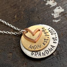 "Custom grandma necklace for a new grandma or one that's well established. Show your grandparent pride with this \"established\" mom and grandma necklace. 1\" handstamped silver alkeme tag is stamped \"Grandma est.\" with date you became (or will become) a grandma. 3/4\" solid brass disc stamped \"Mom est.\" with date you became a mom. 1/2\" copper heart charm. All pieces are hand stamped letter by letter in true artisan style. Edges are beveled and each has a brushed satin finish. Hangs from a Custom Round Necklace For Anniversary And Mother's Day, Custom Round Necklace For Anniversary On Mother's Day, Hand Stamped Round Necklace For Mother's Day, Hand Stamped Round Necklaces For Mother's Day, Meaningful Hand Stamped Necklace For Mom, Anniversary Hand Stamped Round Pendant Necklace, Hand Stamped Necklace For Mother's Day, Meaningful Stamped Necklace For Mother's Day, Meaningful Stamped Necklaces For Mother's Day