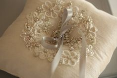 a white pillow with pearls and ribbon on it's side, sitting on a table