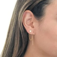 a close up of a woman's face wearing gold earrings with stars on them