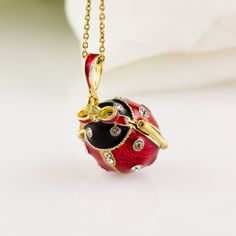 "Bright and festive ladybug locket with heart surprise inside, enameled and 24 K gold plated over solid sterling silver, designed and made in our NJ shop in the tradition of Faberge jewelry. The egg shaped locket ladybug with bright red wings and a black head, will open to show the heart inside the locket, steadily fixed in its place. Clear Swarovski crystals are set in the center of the heart, as well as in the dots of the bug and its eyes. The locket is almost 1\"(25 mm) long. You will receive Luxury Red Enamel Necklaces, Enamel Jewelry For Gifts, Black Enamel Necklace For Gift, Gift Black Enamel Necklace, Heart Pendant Enamel Necklace Gift, Enamel Heart Pendant Necklace As Gift, Heart Pendant Enamel Necklace For Gift, Red Enamel Collectible Jewelry, Red Round Jewelry With Black Enamel