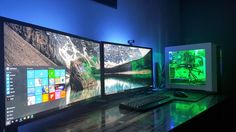 three computer monitors sitting on top of a wooden desk