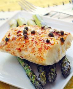 a white plate topped with fish and asparagus