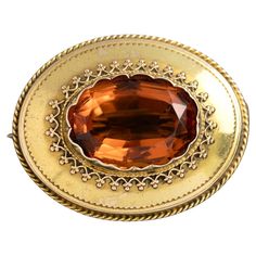 One Victorian yellow gold brooch featuring a central oval cut rich orange citrine quartz surrounded by fine wire work and engraving. Secured with a metal pin and hook catch. Due to the age and wear of this antique piece, there is evidence of a previous lead solder repair on the hinge of the brooch. Gemstone: One oval madeira citrine, estimated weight 11.30ct Metal: 15k yellow gold Weight: 7.60 grams Measurements: Length 4.0cm, width 2.5cm Era: Victorian Circa 1880s The Victorian era was one of romance. Queen Victoria was madly in love with her Albert, and the jewellery swayed in style accordingly. Orange Citrine, 12 Dancing Princesses, Gold Brooch, Gold Brooches, Metal Pins, Queen Victoria, Wire Work, Victorian Era, Oval Cut