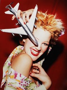 a woman with scissors on her head posing for a photo in front of a red background